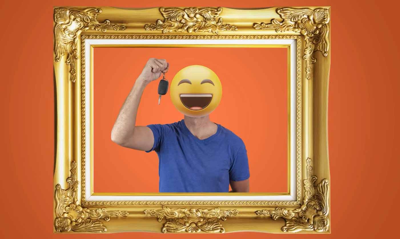 Person mit lachendem Smileykopf hat einen Autoschlüssel in der Hand und ist umrahmt mit einem altem Holzrahmen.